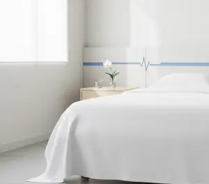 Эстетичный натюрморт с белым постельным бельем, стаканом воды и мягким утренним светом